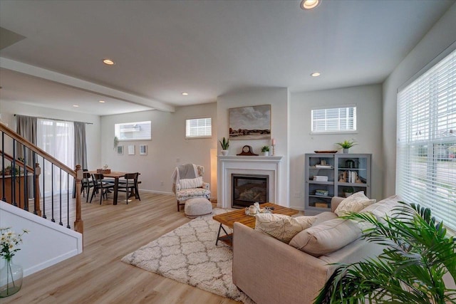 living room featuring beamed ceiling and light wood-type flooring