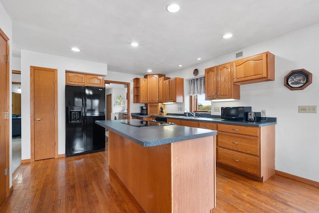 kitchen featuring sink, hardwood / wood-style flooring, black appliances, and a kitchen island