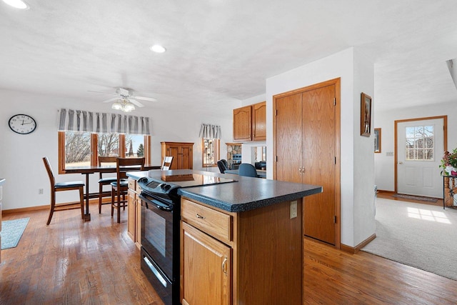 kitchen with wood-type flooring, a center island, black electric range oven, and ceiling fan