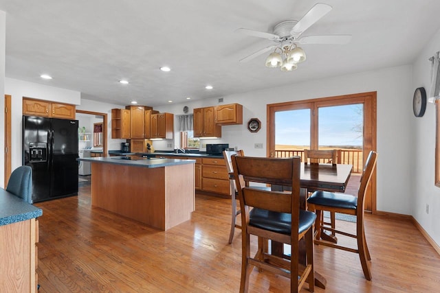 kitchen with a kitchen island, black appliances, sink, ceiling fan, and light hardwood / wood-style floors