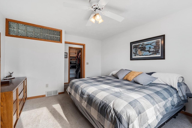 carpeted bedroom with a spacious closet, ceiling fan, and a closet