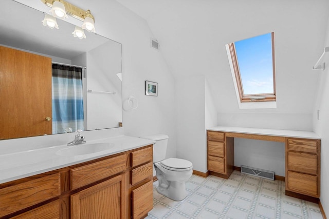 bathroom with vanity, toilet, and vaulted ceiling with skylight