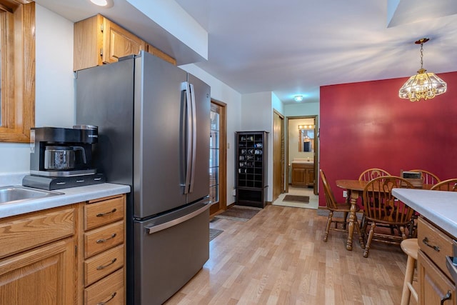 kitchen featuring an inviting chandelier, pendant lighting, stainless steel fridge, and light wood-type flooring