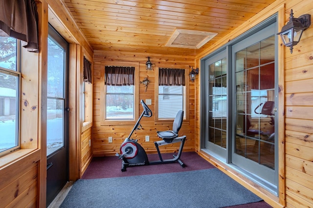 exercise room with wood ceiling, wooden walls, and dark colored carpet