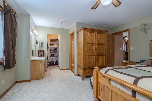 bedroom with a walk in closet, light carpet, ceiling fan, and a closet