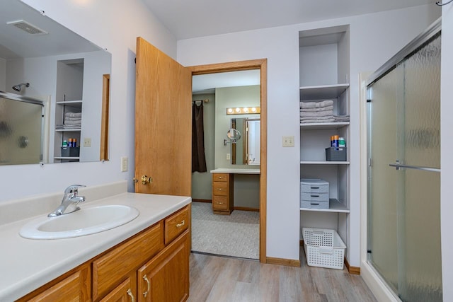 bathroom with hardwood / wood-style flooring, vanity, and an enclosed shower