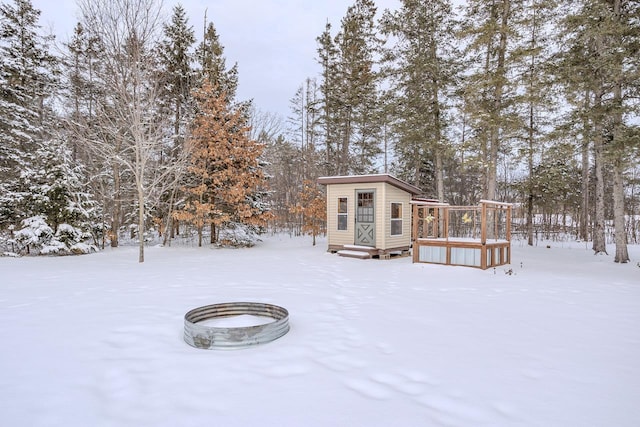 yard covered in snow featuring a wooden deck and an outdoor structure