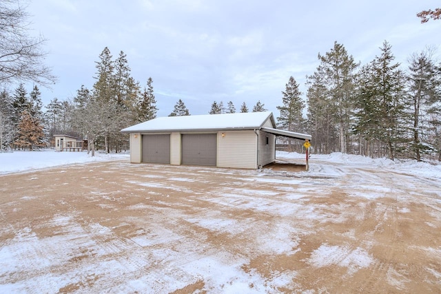 snow covered garage with a carport