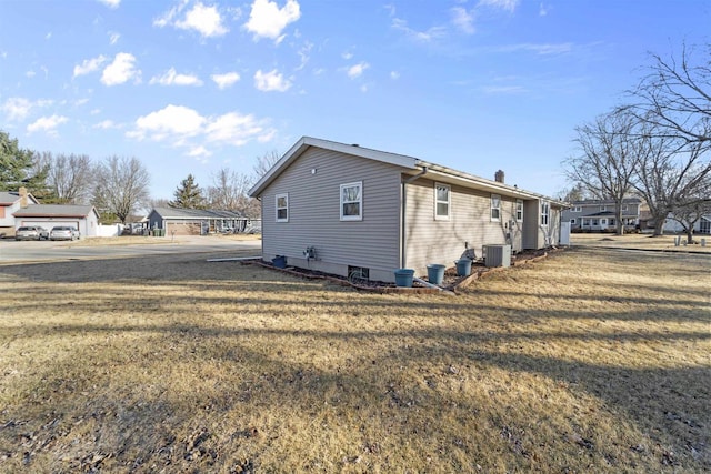 view of side of property with central AC unit and a lawn