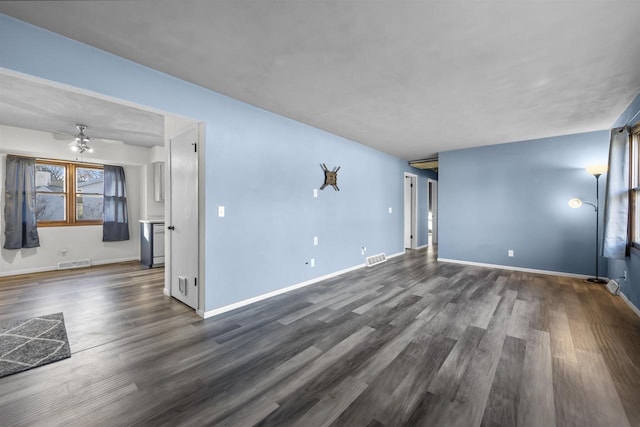 unfurnished living room featuring dark wood-type flooring and ceiling fan