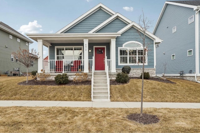 bungalow-style house featuring covered porch and a front lawn