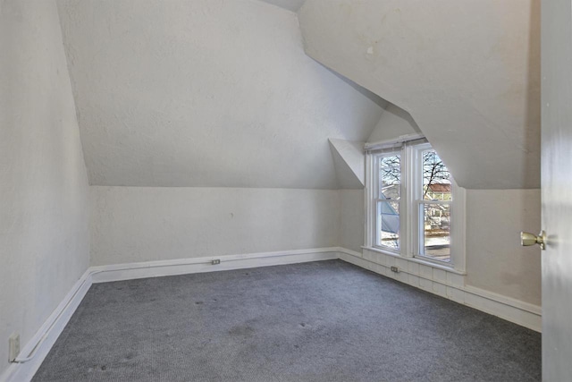 additional living space featuring lofted ceiling and dark carpet