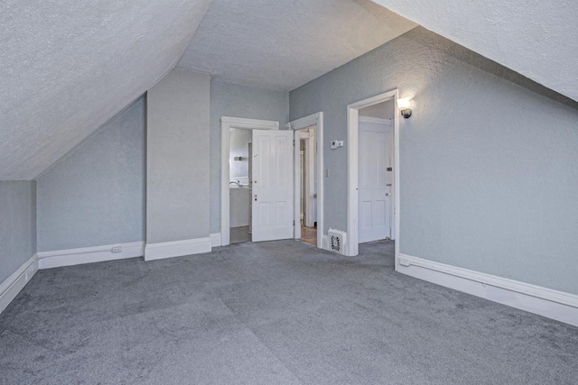 additional living space with lofted ceiling, a textured ceiling, and carpet