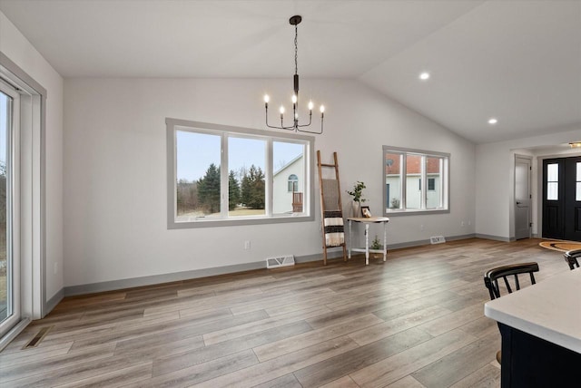 unfurnished dining area with lofted ceiling, a notable chandelier, a wealth of natural light, and light wood-type flooring