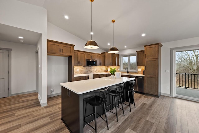 kitchen featuring hardwood / wood-style flooring, appliances with stainless steel finishes, a center island, and hanging light fixtures