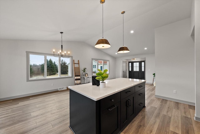 kitchen featuring decorative light fixtures, lofted ceiling, a chandelier, a center island, and light hardwood / wood-style flooring