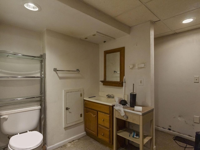 bathroom featuring a drop ceiling, vanity, and toilet