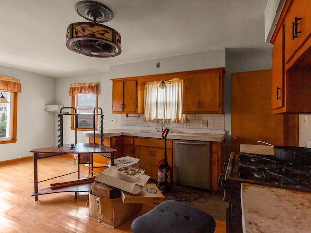 kitchen with tasteful backsplash, a wealth of natural light, stainless steel dishwasher, and range with gas cooktop