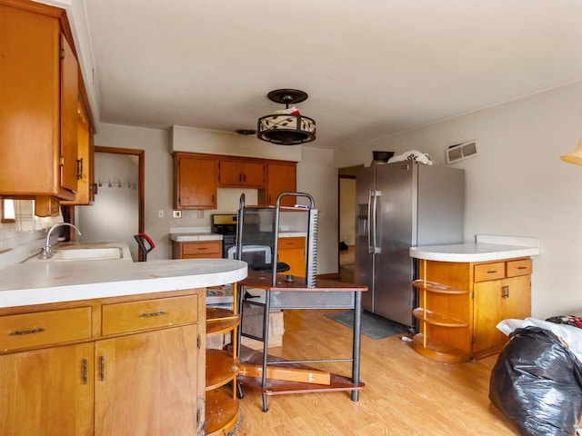 kitchen featuring sink, light wood-type flooring, and stainless steel refrigerator with ice dispenser