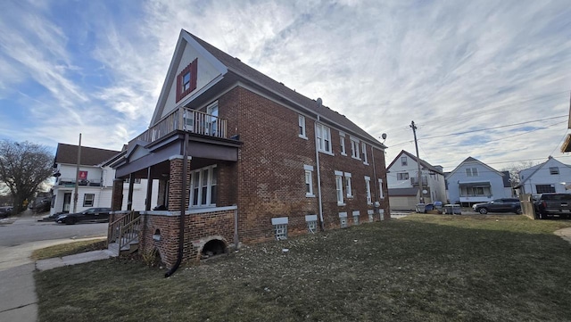 view of side of property featuring a balcony and a yard