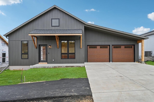 modern farmhouse with a garage, central AC unit, covered porch, and a front lawn