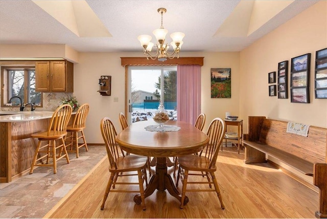 dining room with sink, a notable chandelier, a textured ceiling, and light hardwood / wood-style flooring