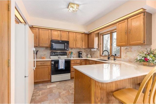 kitchen featuring tasteful backsplash, sink, a breakfast bar area, kitchen peninsula, and white appliances