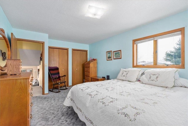 carpeted bedroom with two closets and a textured ceiling