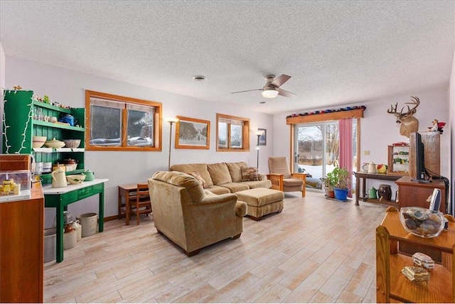 living room featuring ceiling fan, light hardwood / wood-style flooring, and a textured ceiling