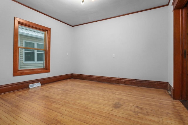 spare room with ornamental molding and light hardwood / wood-style floors