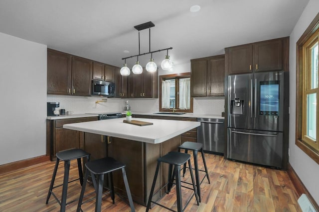 kitchen featuring pendant lighting, stainless steel appliances, a kitchen bar, and sink