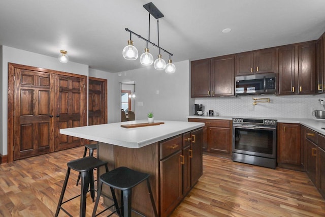 kitchen featuring tasteful backsplash, a kitchen breakfast bar, a center island, stainless steel appliances, and dark wood-type flooring