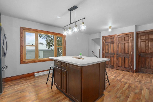 kitchen featuring a kitchen bar, decorative light fixtures, a center island, and hardwood / wood-style floors