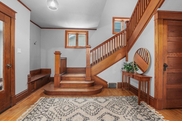 stairs with ornamental molding and wood-type flooring