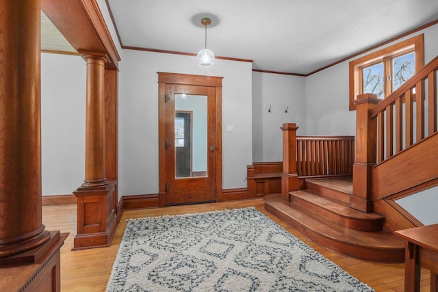 entryway featuring crown molding, light hardwood / wood-style floors, and ornate columns