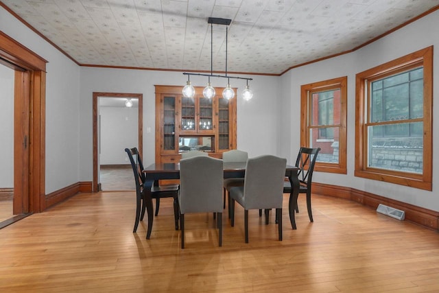 dining room with crown molding and light hardwood / wood-style flooring