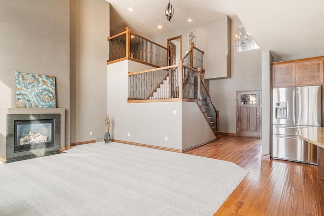 living room with a high ceiling, an inviting chandelier, and light hardwood / wood-style flooring