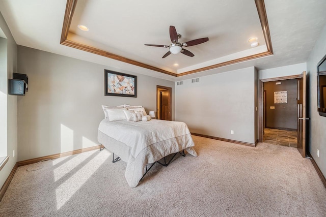 carpeted bedroom featuring ceiling fan and a tray ceiling