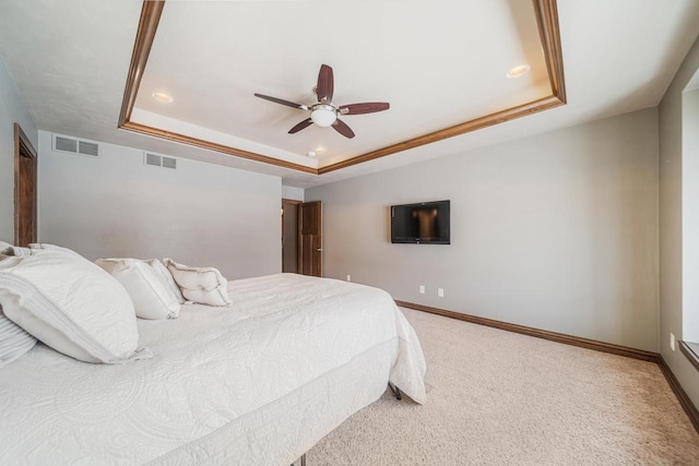 bedroom with ceiling fan, a tray ceiling, and carpet