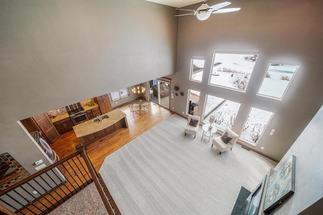 living room featuring ceiling fan, sink, hardwood / wood-style floors, and a high ceiling