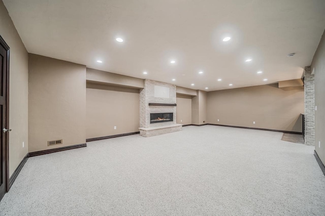 unfurnished living room featuring a stone fireplace and light colored carpet