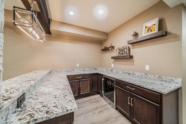 kitchen with light stone counters, dark brown cabinets, light hardwood / wood-style floors, and beverage cooler