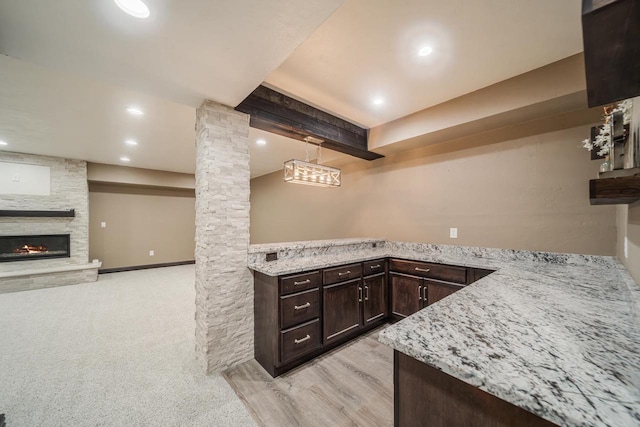 kitchen with pendant lighting, kitchen peninsula, decorative columns, and light stone countertops