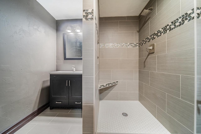 bathroom with tile patterned floors, vanity, and a tile shower