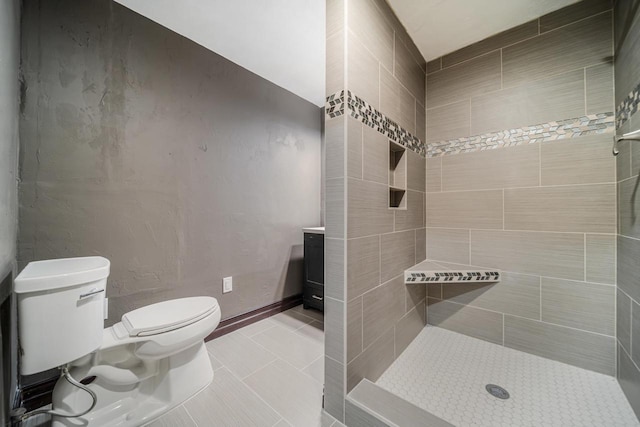 bathroom featuring tile patterned flooring, a tile shower, and toilet