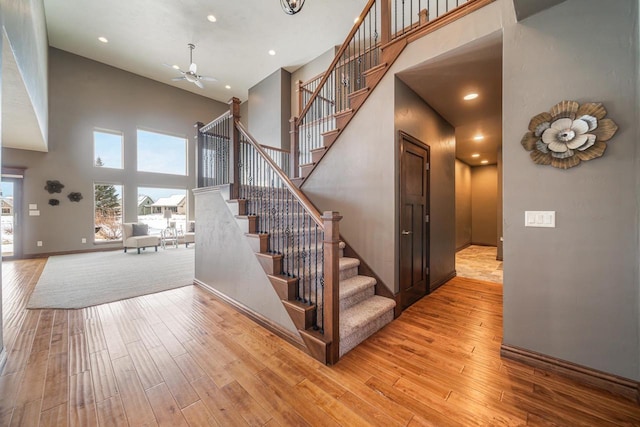 staircase with hardwood / wood-style flooring, ceiling fan, and a high ceiling