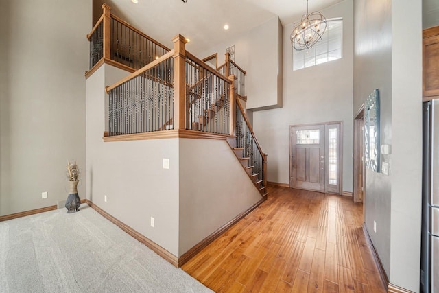 foyer entrance with a notable chandelier, wood-type flooring, and a high ceiling