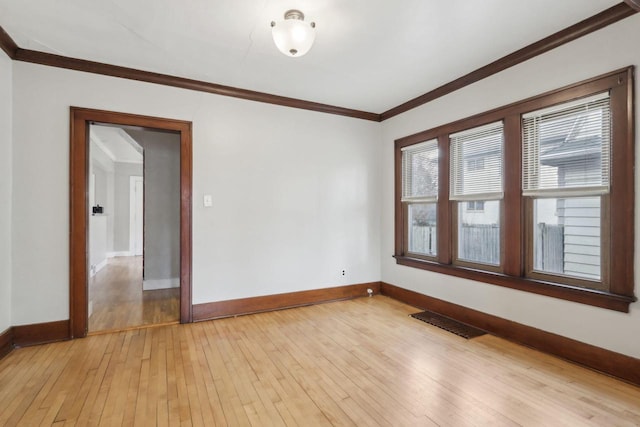 empty room featuring ornamental molding and light wood-type flooring