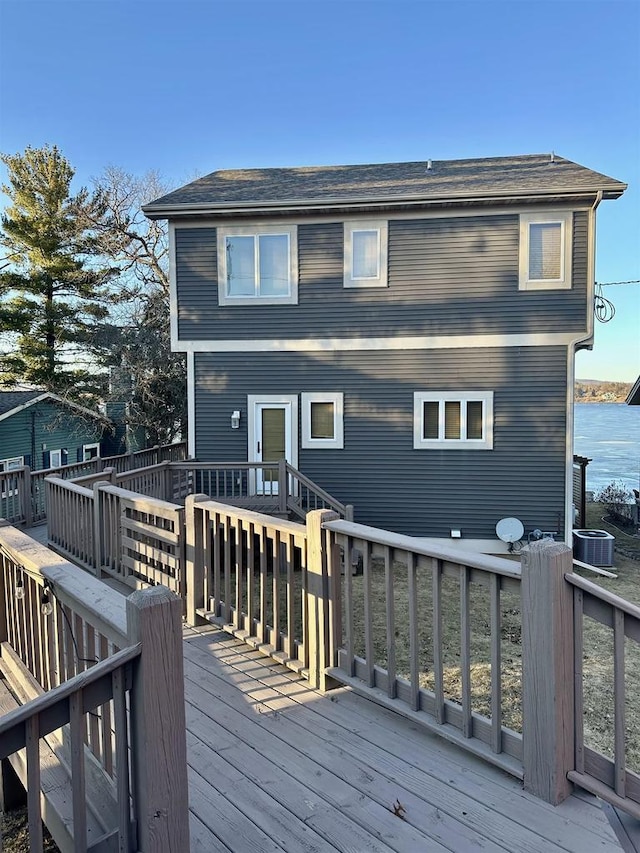 rear view of property featuring a deck with water view and cooling unit