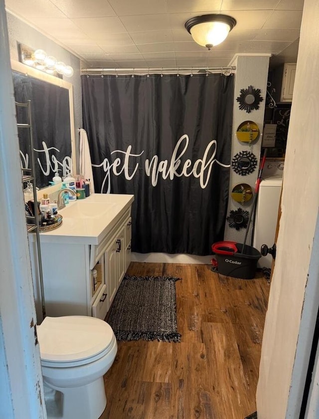 bathroom featuring hardwood / wood-style flooring, vanity, toilet, and washer / dryer